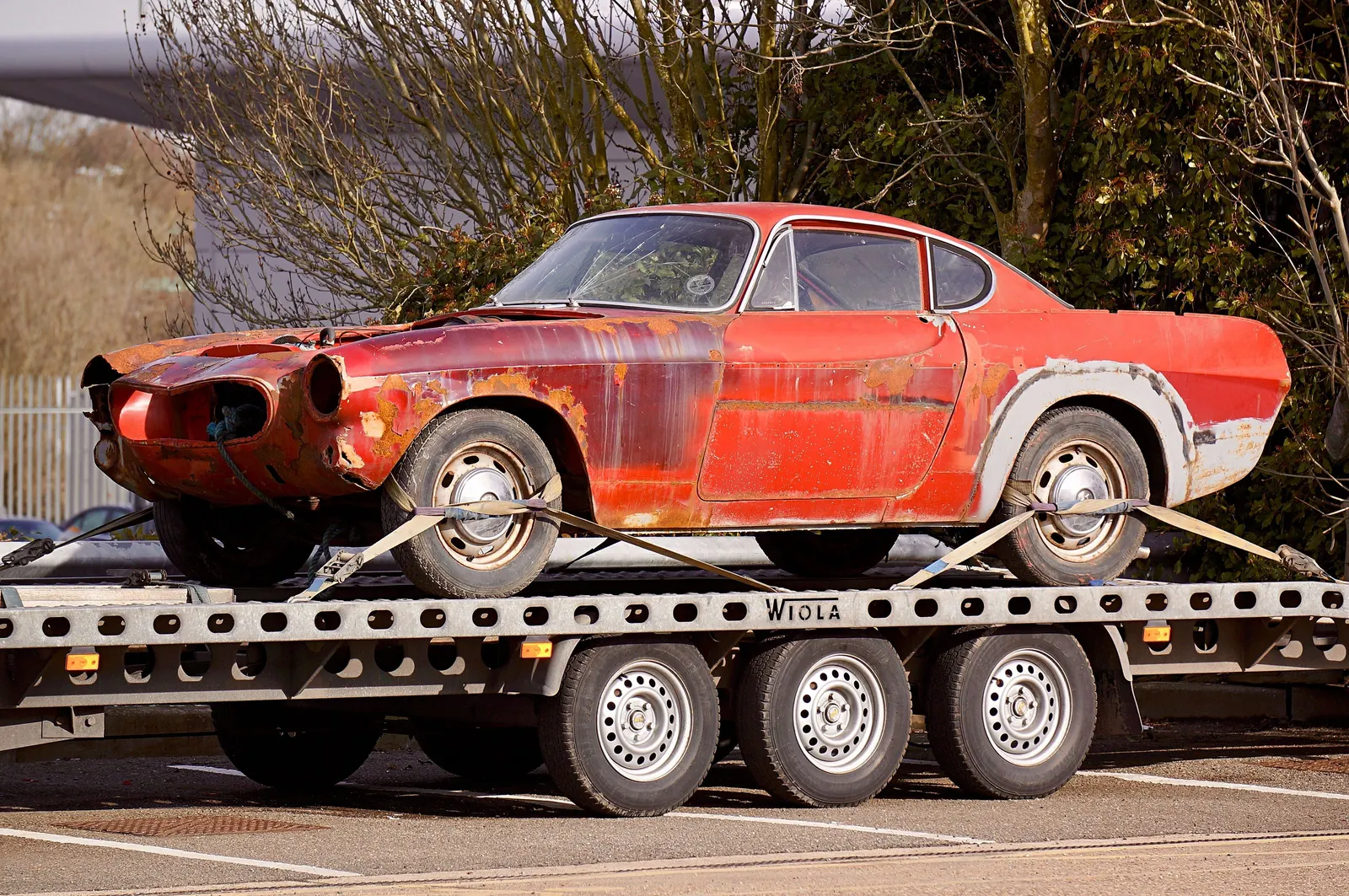 Auto auf einem Autotransport-Anhänger mit Spanngurten gesichert
