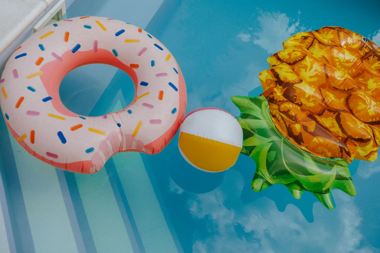 A vibrant display of fun pool floats and beach ball in a clear swimming pool.